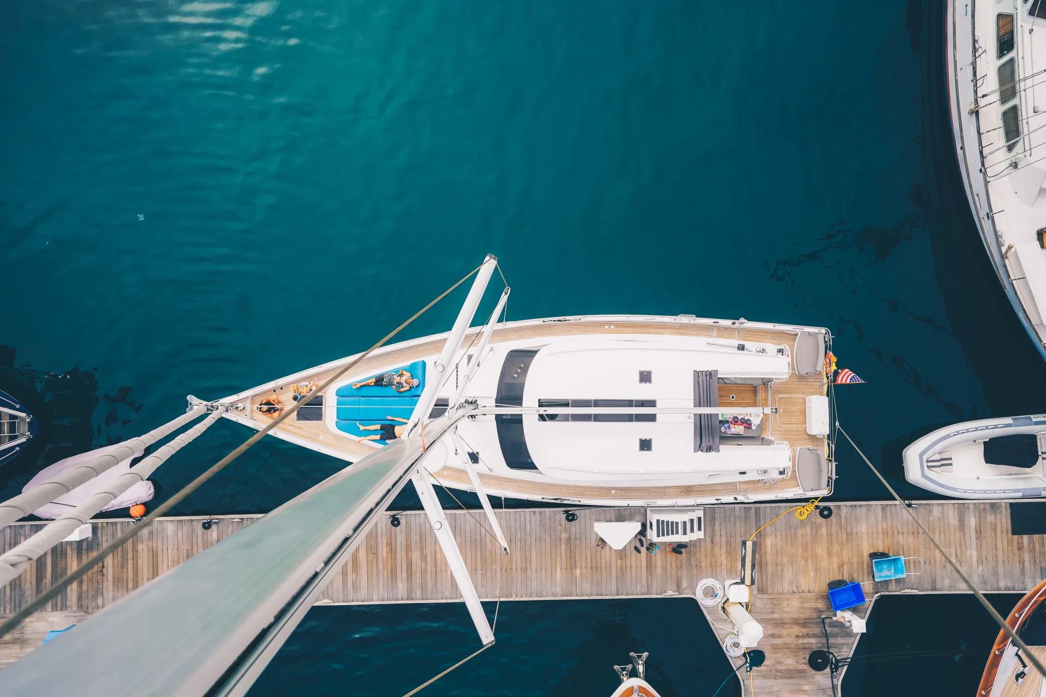 Overhead view of a white sailing yacht moored at a dock in deep blue water