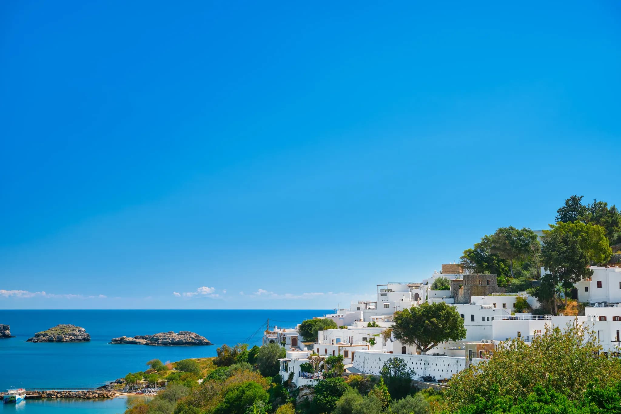 A whitewashed Greek hillside village overlooking a calm turquoise bay